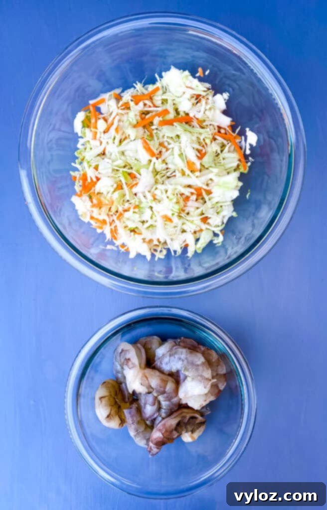 Fresh, raw shrimp and a bowl of crisp coleslaw mix, ready for preparing delicious homemade egg rolls.