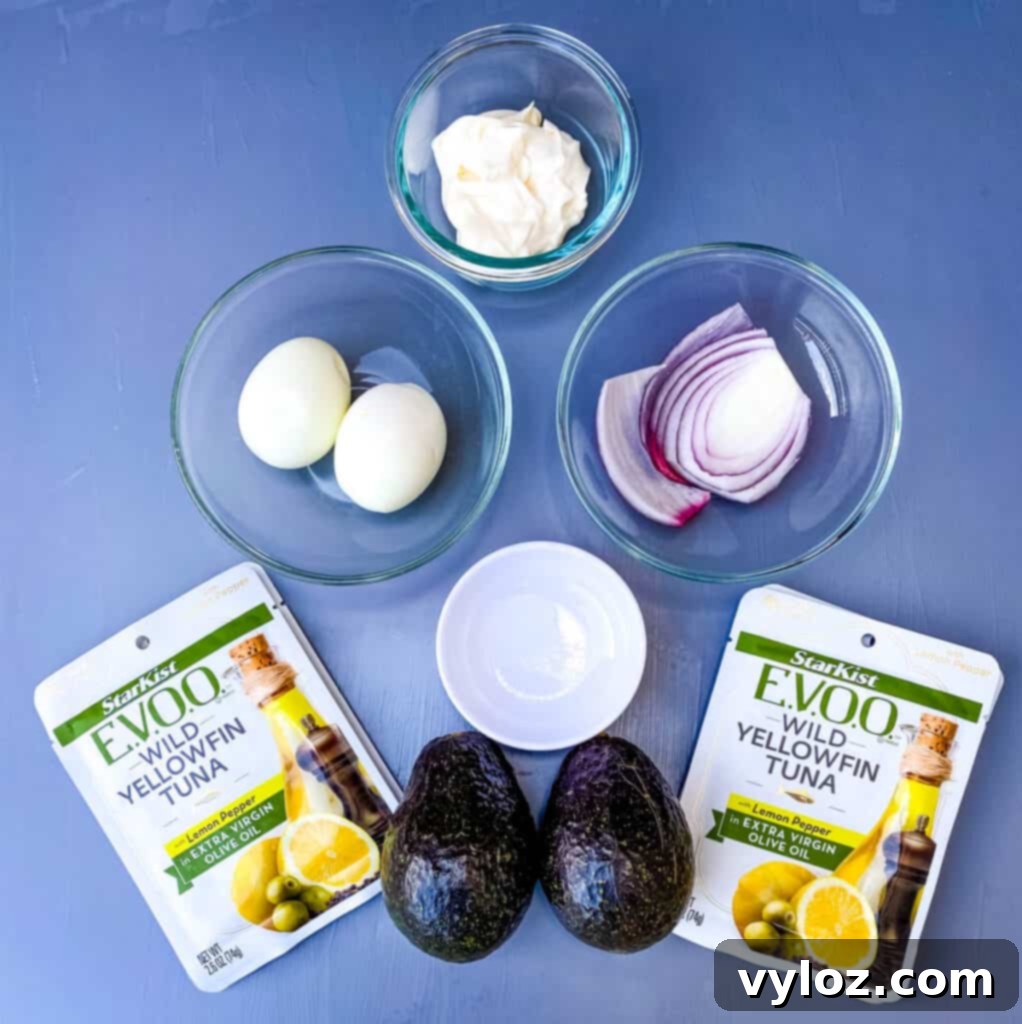boiled eggs, mayo, onions, avocado, and packaged tuna on a flat surface