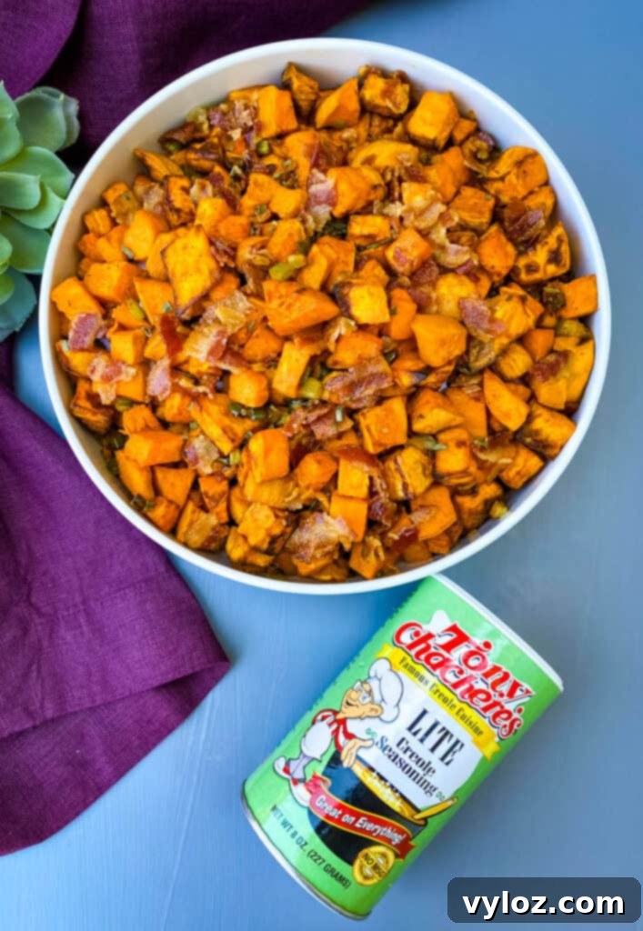Crispy Air Fryer Sweet Potato Hash 11 Another view of air fryer sweet potato hash with chopped bacon in a white bowl, along with a bottle of Creole seasoning.