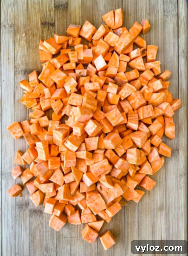Crispy Air Fryer Sweet Potato Hash 4 Diced, raw sweet potatoes neatly arranged on a bamboo cutting board, ready for seasoning.