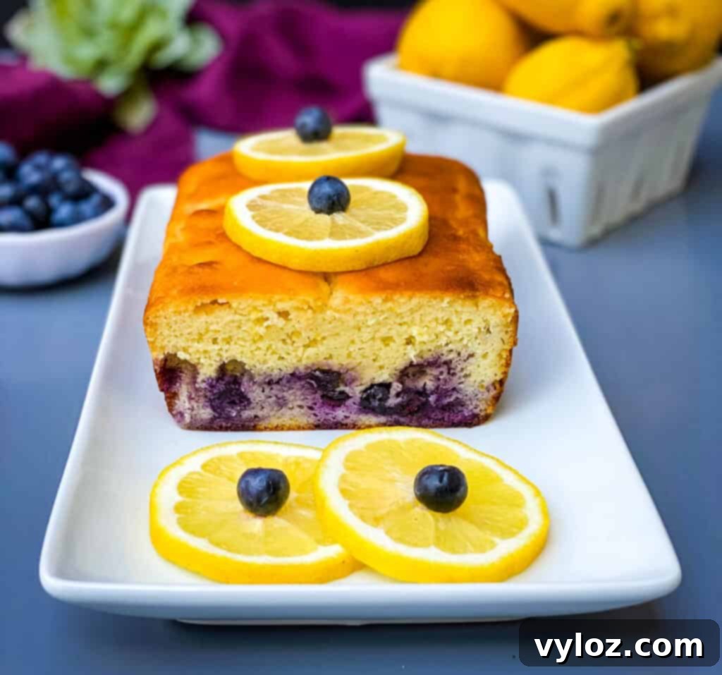 keto low carb lemon blueberry bread on a white plate with fresh lemons and blueberries