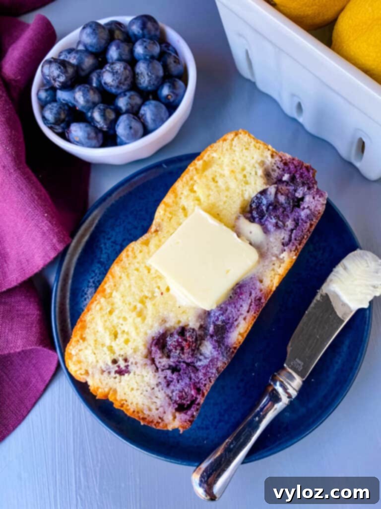 a slice of keto lemon blueberry bread on a blue plate with butter