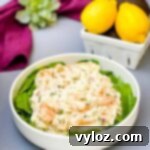Effortless Crab Salad 11 seafood crab salad with shrimp in a white bowl with spinach and a bowl of lemons
