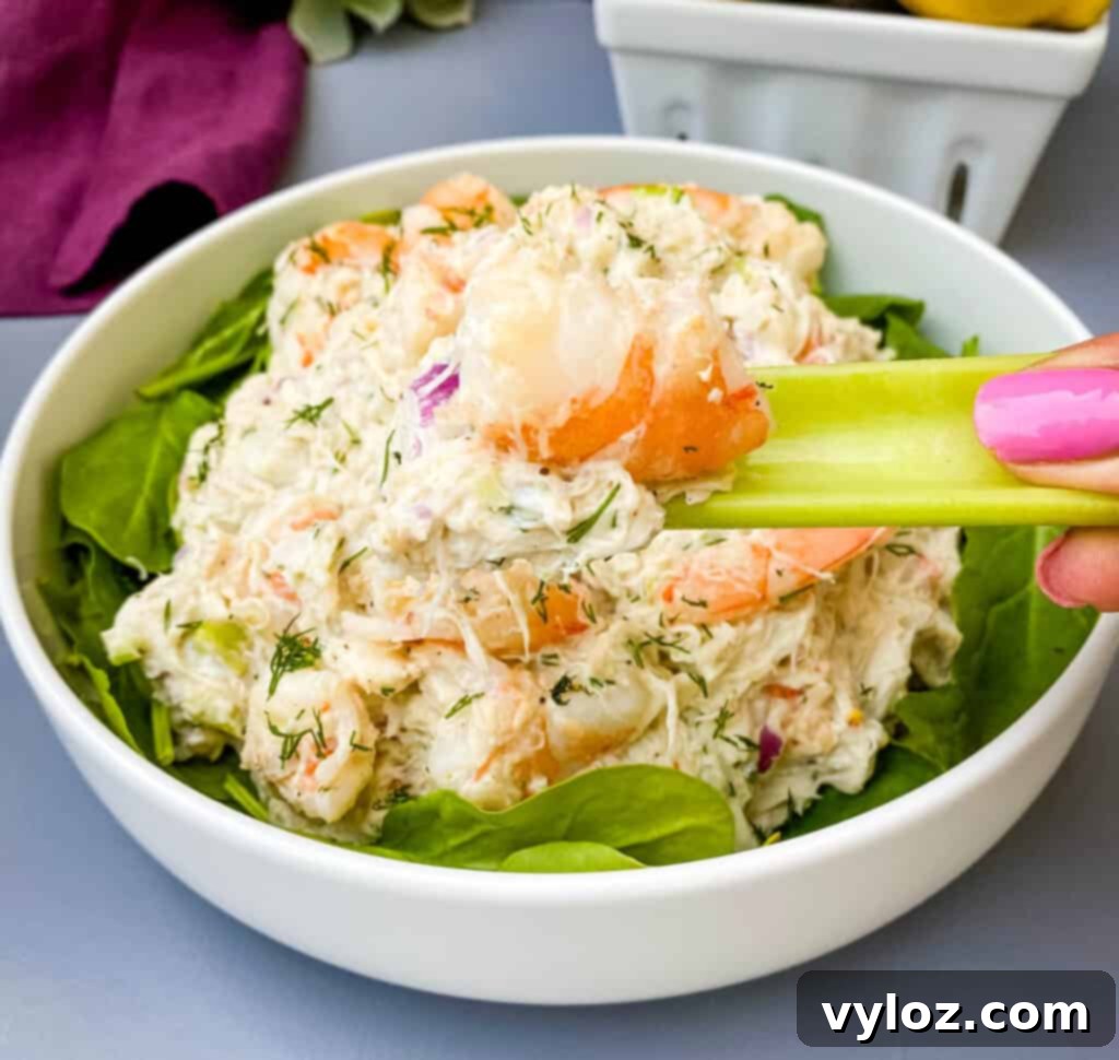 Effortless Crab Salad 10 person holding a stalk of celery with seafood salad