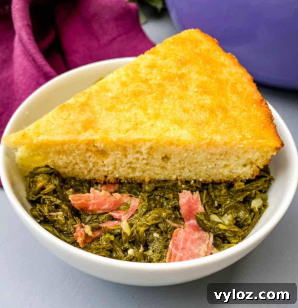 A rustic bowl of Southern mustard greens with shredded smoked turkey and a slice of golden cornbread, a classic comfort meal.