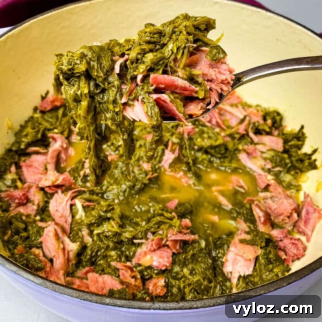 A spoonful of tender, cooked mustard greens held over a steaming Dutch oven, showcasing their perfect texture.