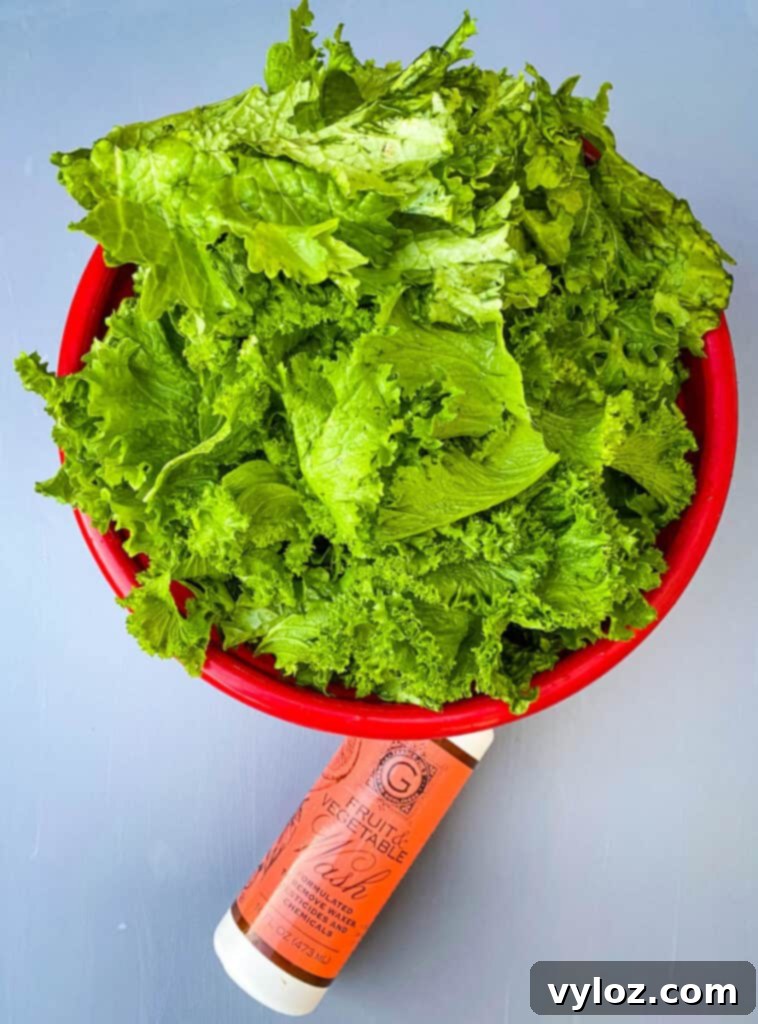 Raw and fresh mustard greens in a red bowl, accompanied by a bottle of produce cleaner, ready for washing.