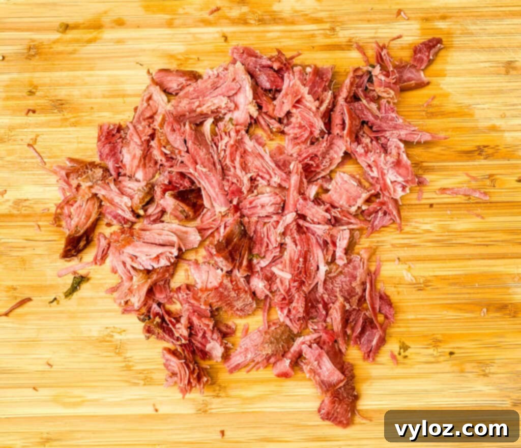 Shredded smoked turkey meat displayed on a bamboo cutting board, ready to be added to the greens.