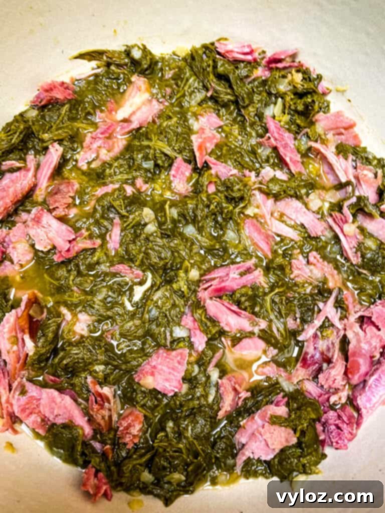 Cooked Southern mustard greens simmering in a Dutch oven, with a smoked turkey leg nestled among them, creating rich flavors.