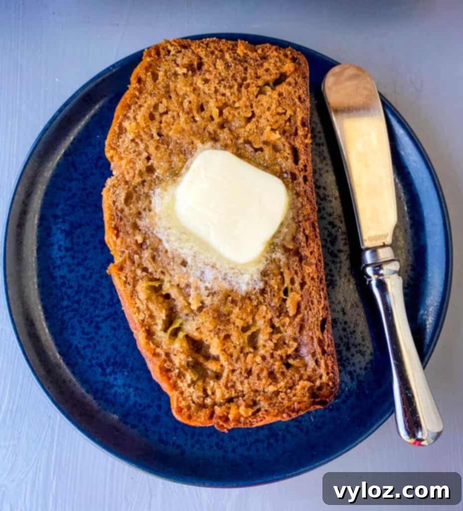 A single slice of healthy banana bread on a blue plate, topped with a pat of butter, ready to be enjoyed