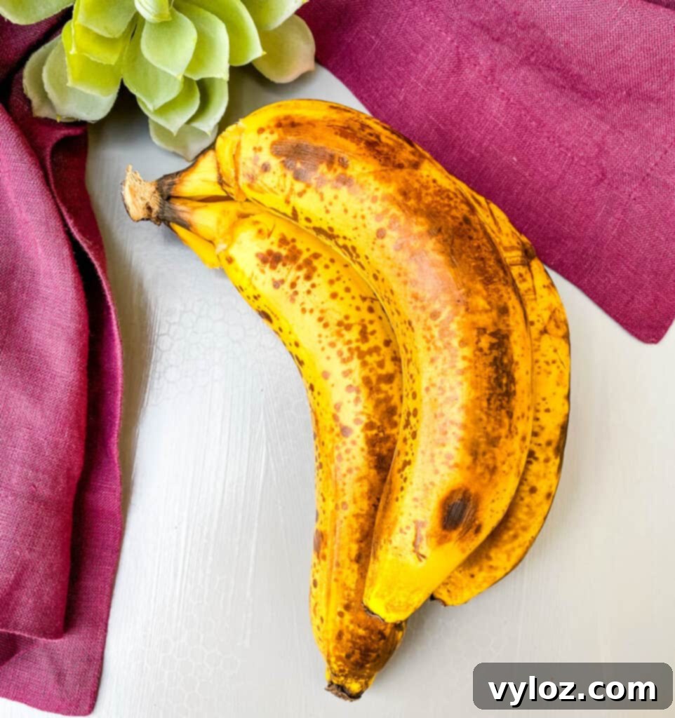 A close-up of overripe bananas with dark brown spots on their skins, indicating ideal ripeness for baking