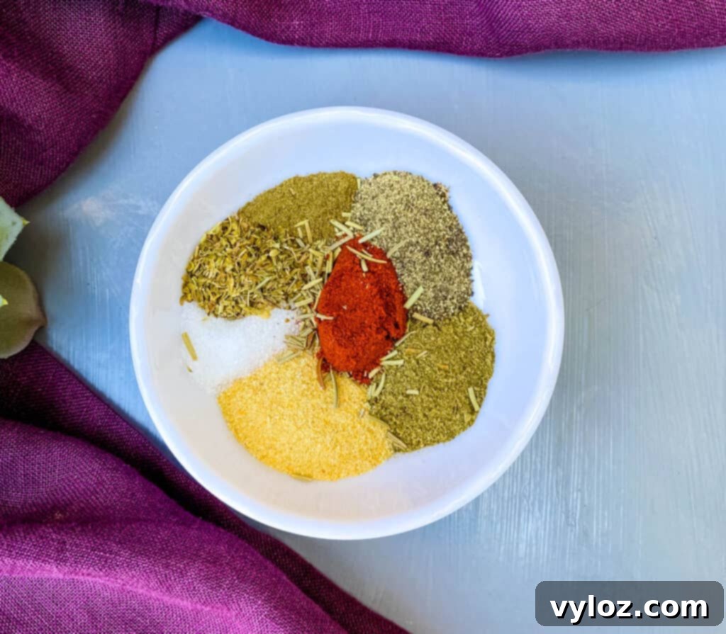 Succulent Air Fryer Cornish Hens 2 Two golden-brown air fryer Cornish hens with crispy skin, garnished with fresh herbs on a rustic wooden board.