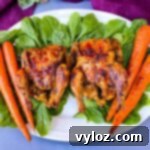 Succulent Air Fryer Cornish Hens 8 Air fryer Cornish hens, fresh spinach, and carrots on a white plate, showcasing a delicious meal.