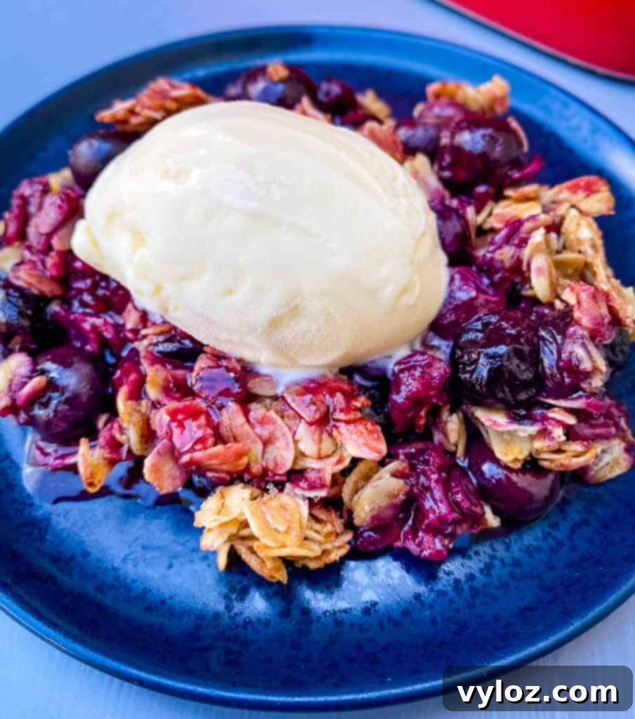 healthy blueberry crisp on a blue plate with a scoop of vanilla ice cream