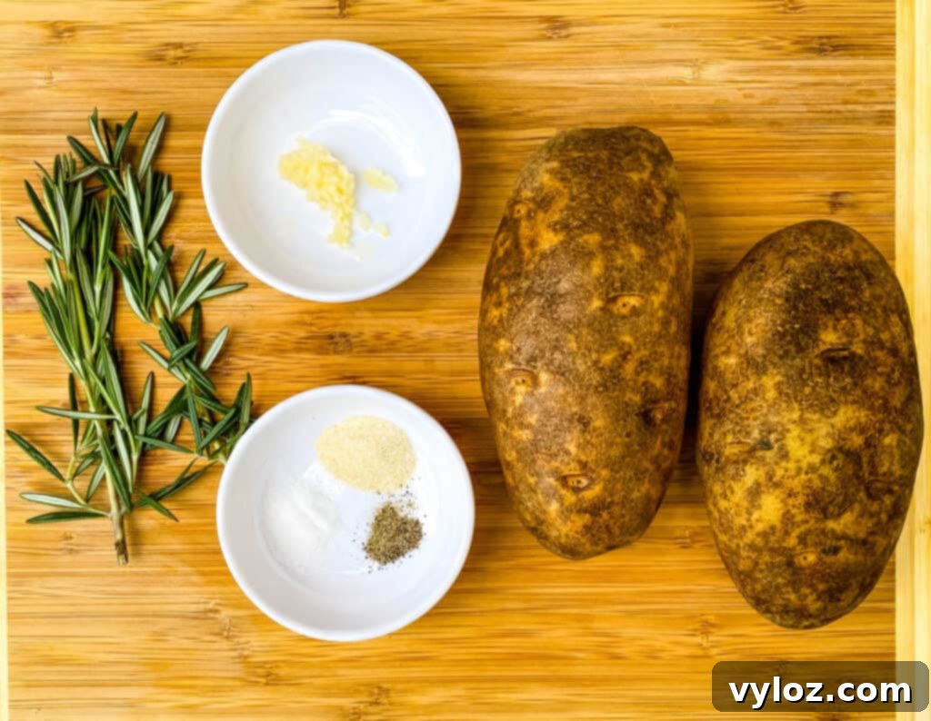 Crispy Air Fryer Roasted Potatoes 3 russet potatoes, garlic, and rosemary on a bamboo cutting board