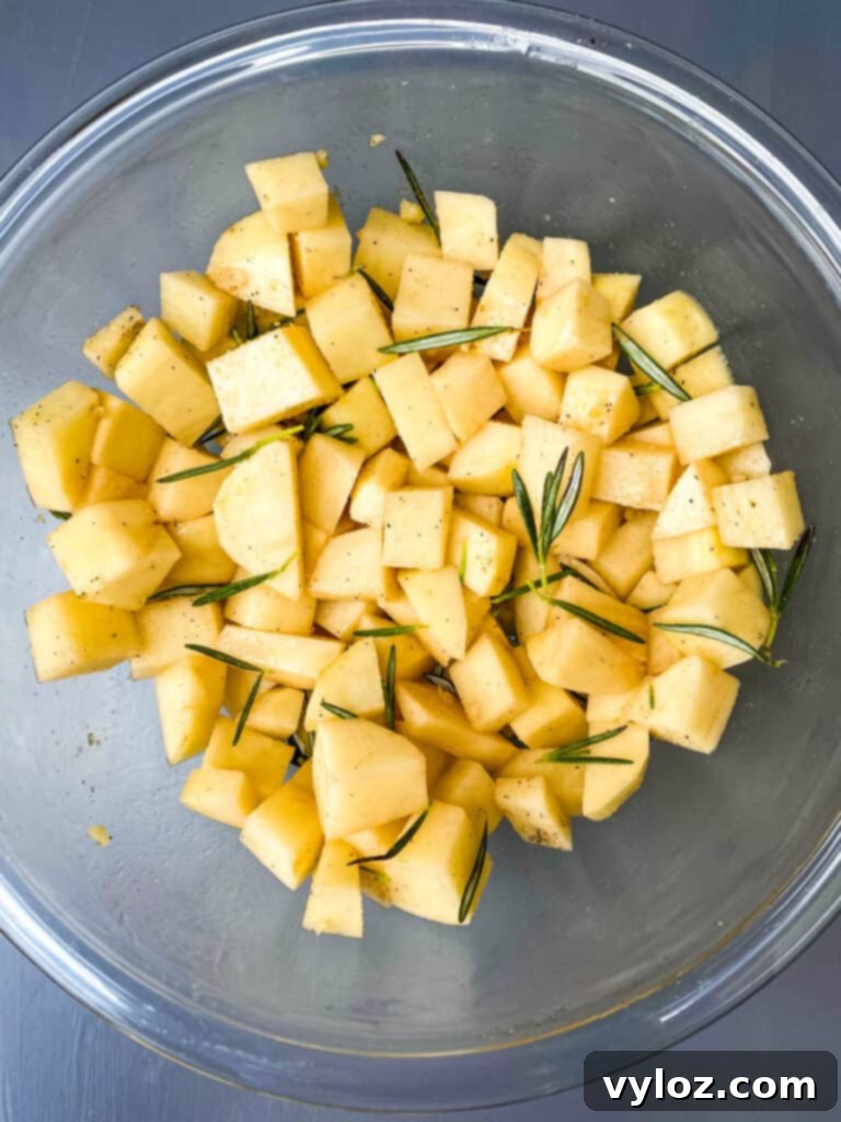 Crispy Air Fryer Roasted Potatoes 4 sliced potatoes in a glass bowl with rosemary