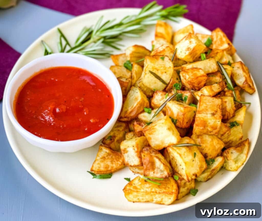 Crispy Air Fryer Roasted Potatoes 8 air fryer roasted potatoes on a white plate with ketchup