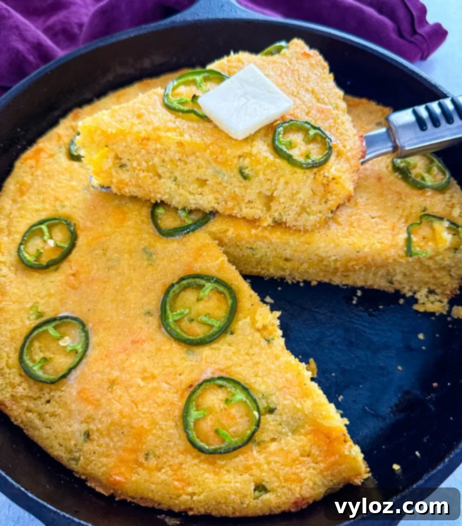 Zesty Cheddar Jalapeño Cornbread 2 jalapeno cheddar cornbread with butter in a cast iron skillet