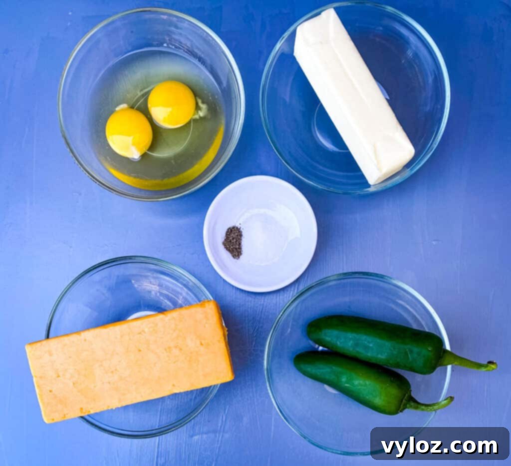 Zesty Cheddar Jalapeño Cornbread 3 raw eggs, butter, cheddar cheese, fresh jalapenos, and salt and pepper on a flat surface
