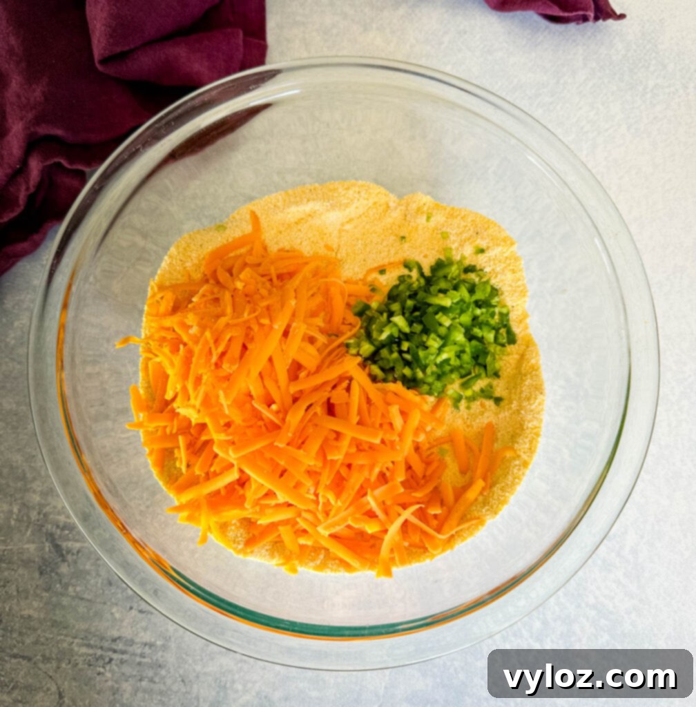 Zesty Cheddar Jalapeño Cornbread 4 cornmeal, cheddar cheese, jalapenos, baking powder, and flour in a glass bowl