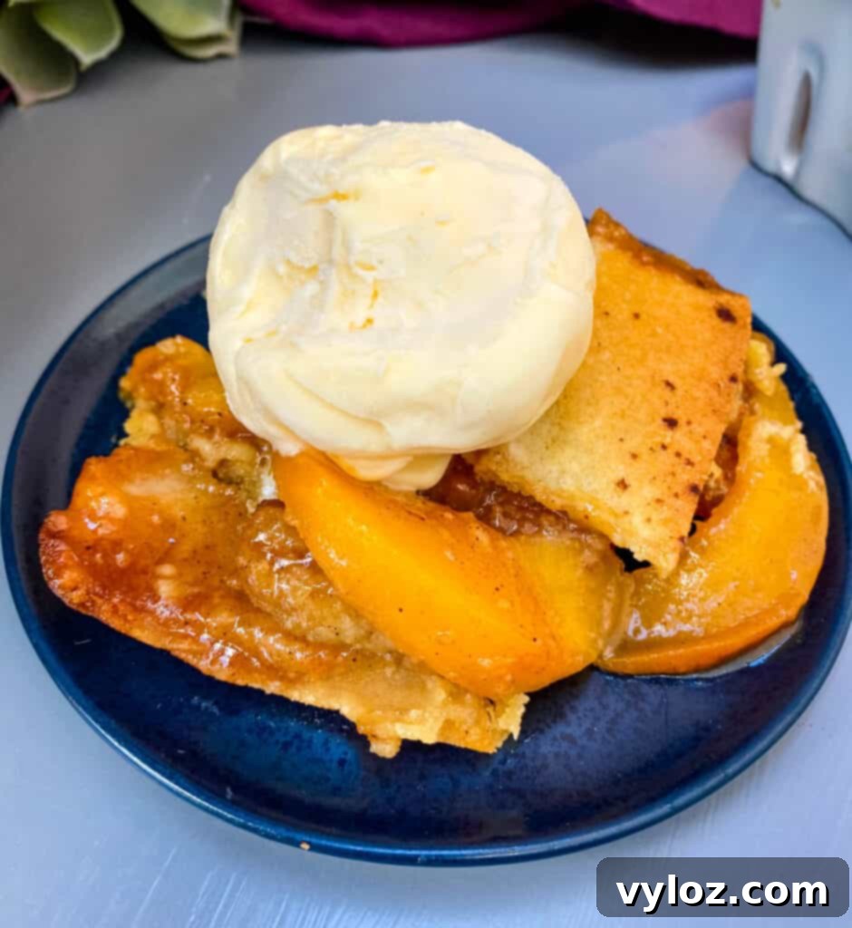 Healthy Southern peach cobbler on a blue plate with vanilla ice cream, ready to be enjoyed