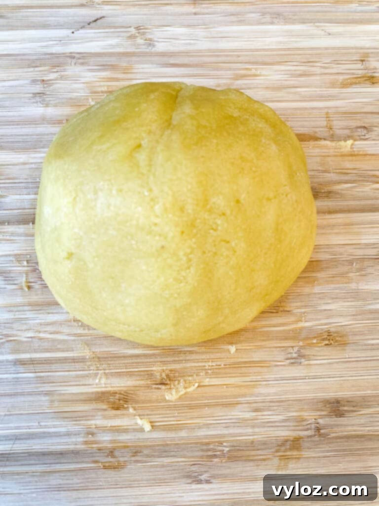 Almond flour crust dough rolled into a ball and a flattened piece on a flat surface