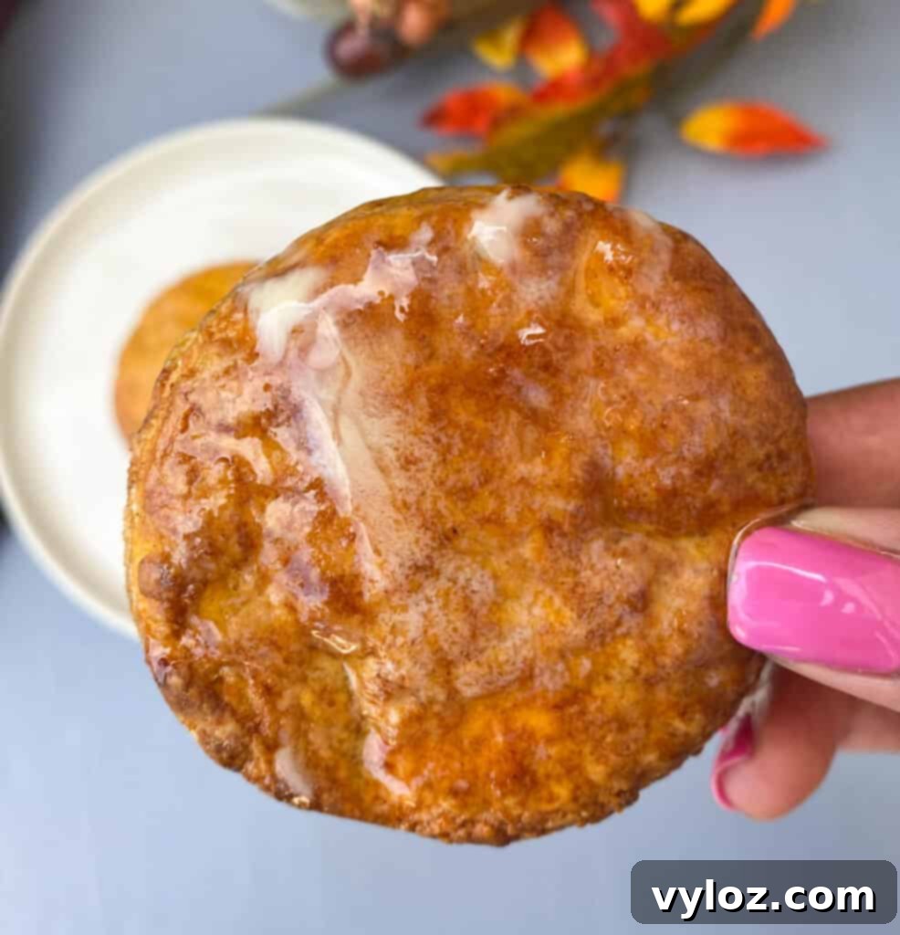 Deliciously Easy Sweet Potato Biscuits 14 A hand holding a warm sweet potato biscuit, topped with melted butter and honey, ready to eat.