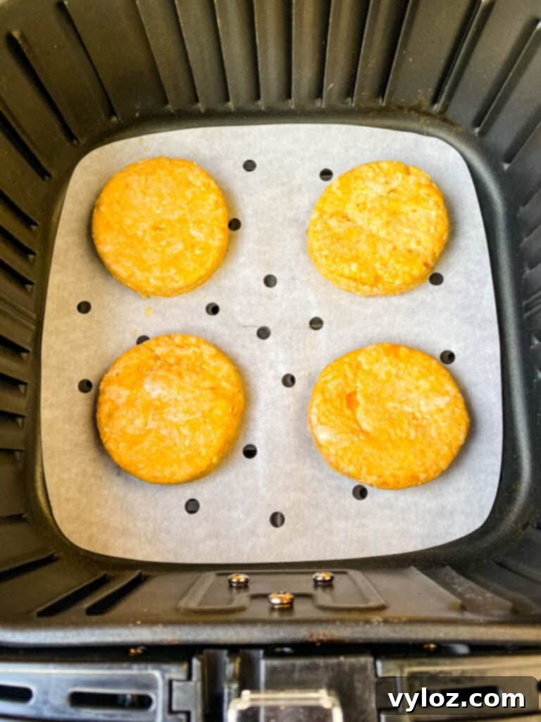 Deliciously Easy Sweet Potato Biscuits 9 Sweet potato biscuits perfectly arranged inside an air fryer basket, cooking to golden perfection.