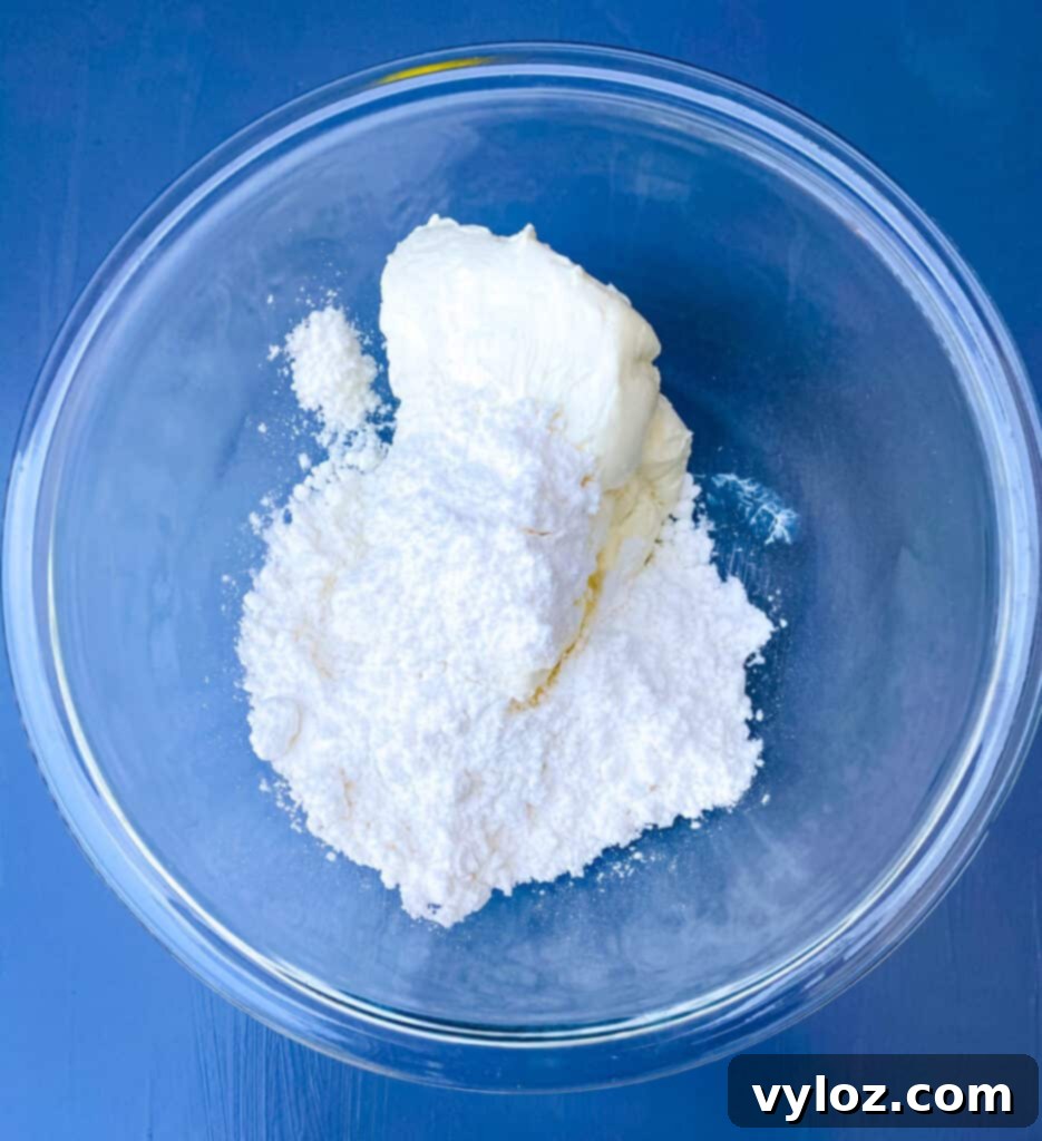 Cream cheese and powdered sweetener being mixed in a glass bowl