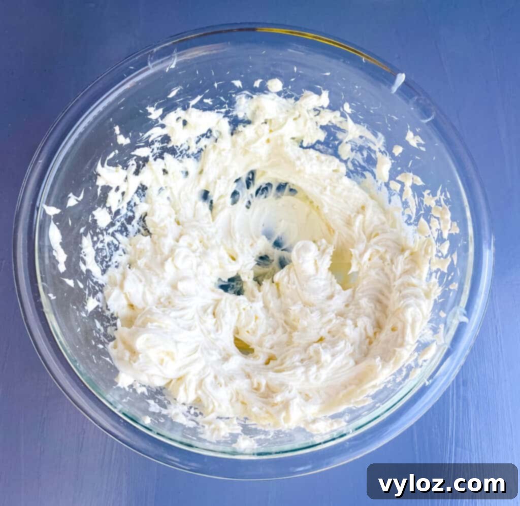 Keto cheesecake filling in a glass bowl after mixing initial ingredients