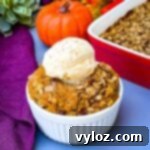 healthy pumpkin crisp in a white bowl with a scoop of vanilla ice cream