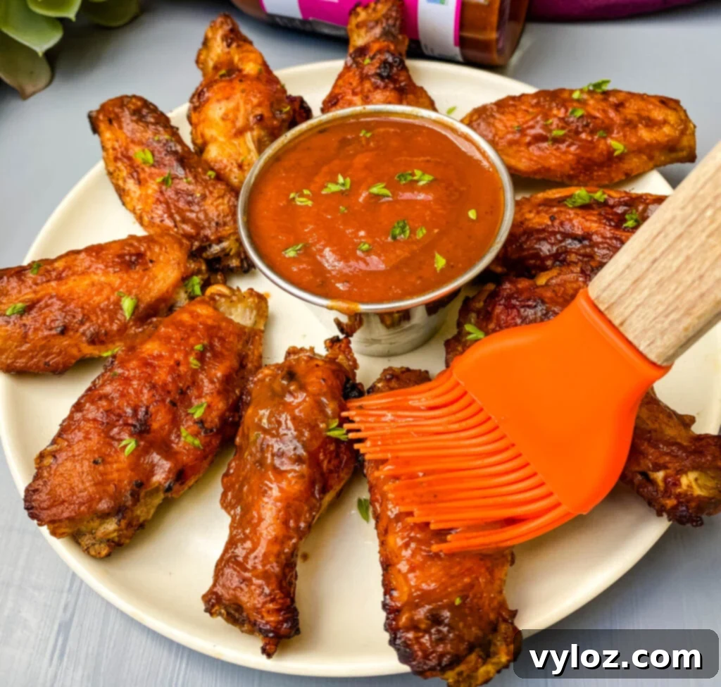 air fryer bbq chicken on a plate with bbq sauce with a cooking brush drizzling sauce over the chicken