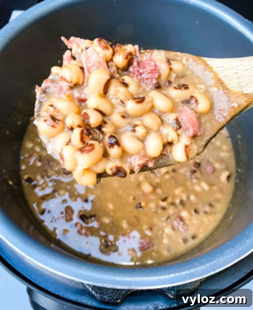 A wooden spoon scooping black eyed peas from an Instant Pot, showing their tender texture