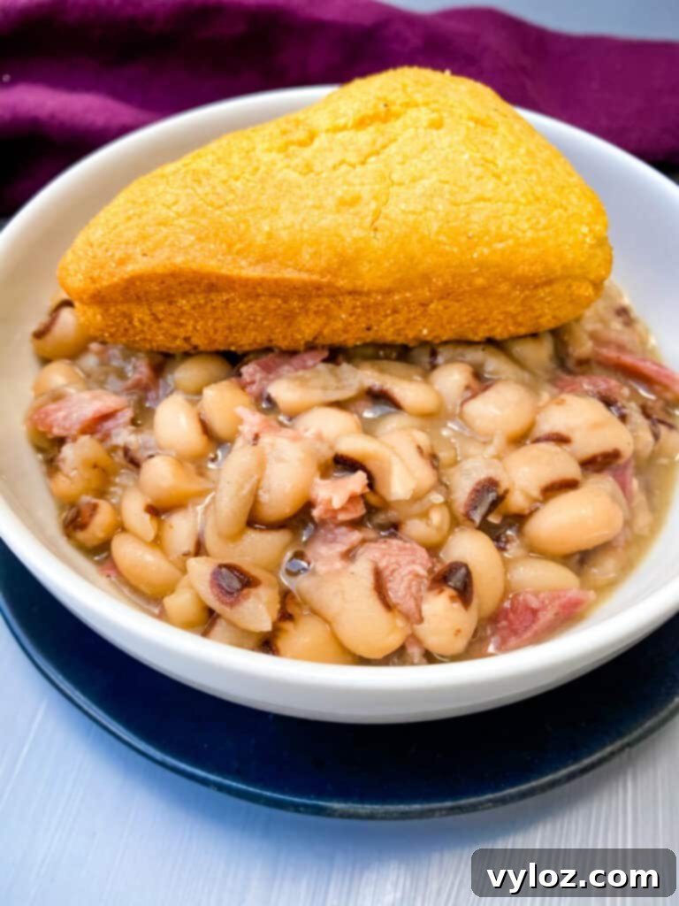 Instant Pot black eyed peas in a white bowl, served with cornbread on the side