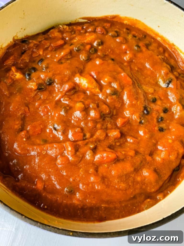 Autumnal Pumpkin Chicken Chili 6 A close-up shot of Pumpkin Chicken Chili simmering in a rich purple Dutch oven, showcasing its hearty texture and vibrant color.