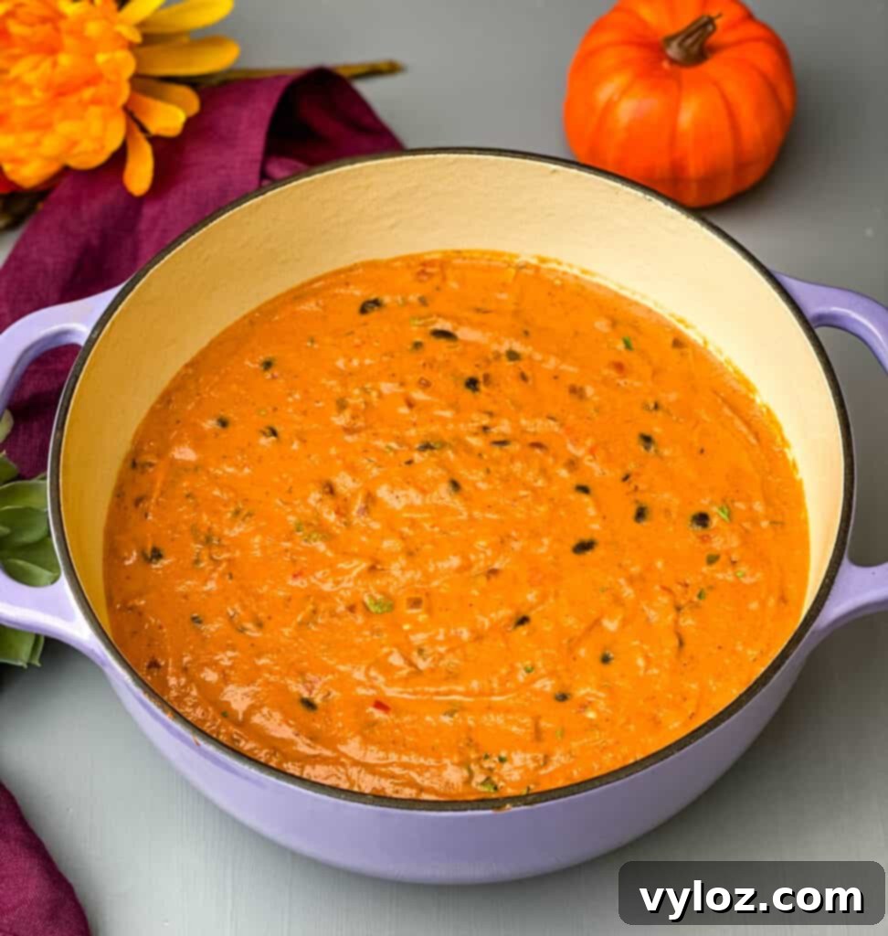 Autumnal Pumpkin Chicken Chili 8 Pumpkin Chicken Chili simmering robustly in a purple Dutch oven, its surface rich with vibrant colors and hearty ingredients, ready to be served.