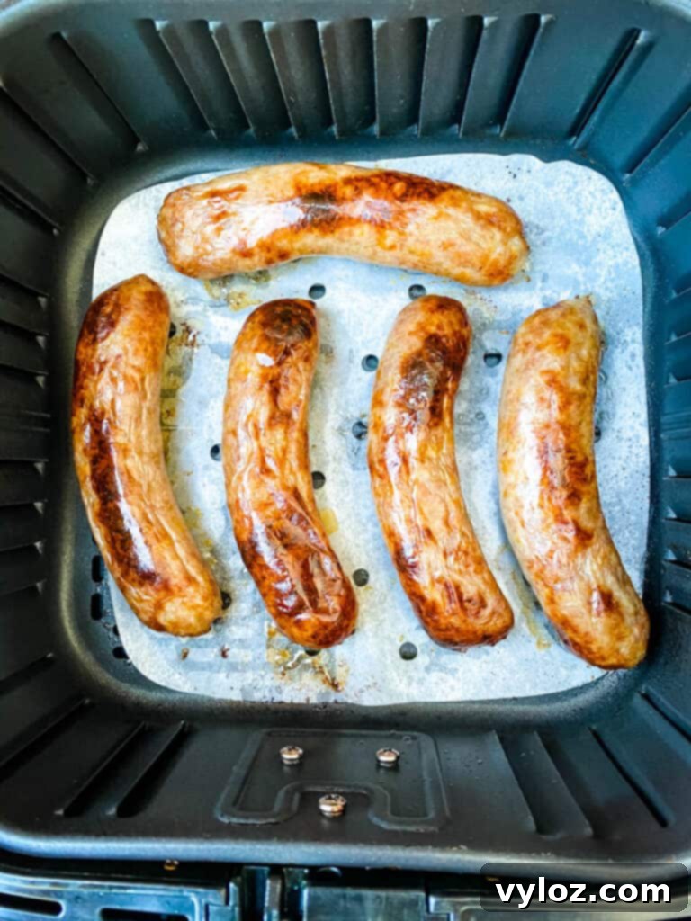 cooked brats with crispy skin in an air fryer basket