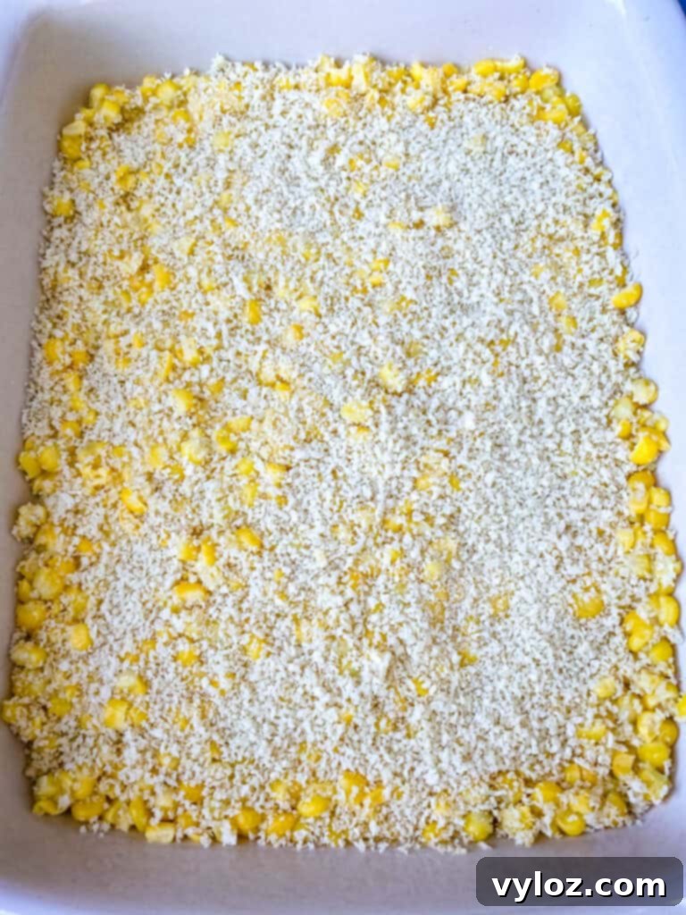 A close-up of uncooked scalloped corn in a baking dish, highlighting the texture and readiness for baking.