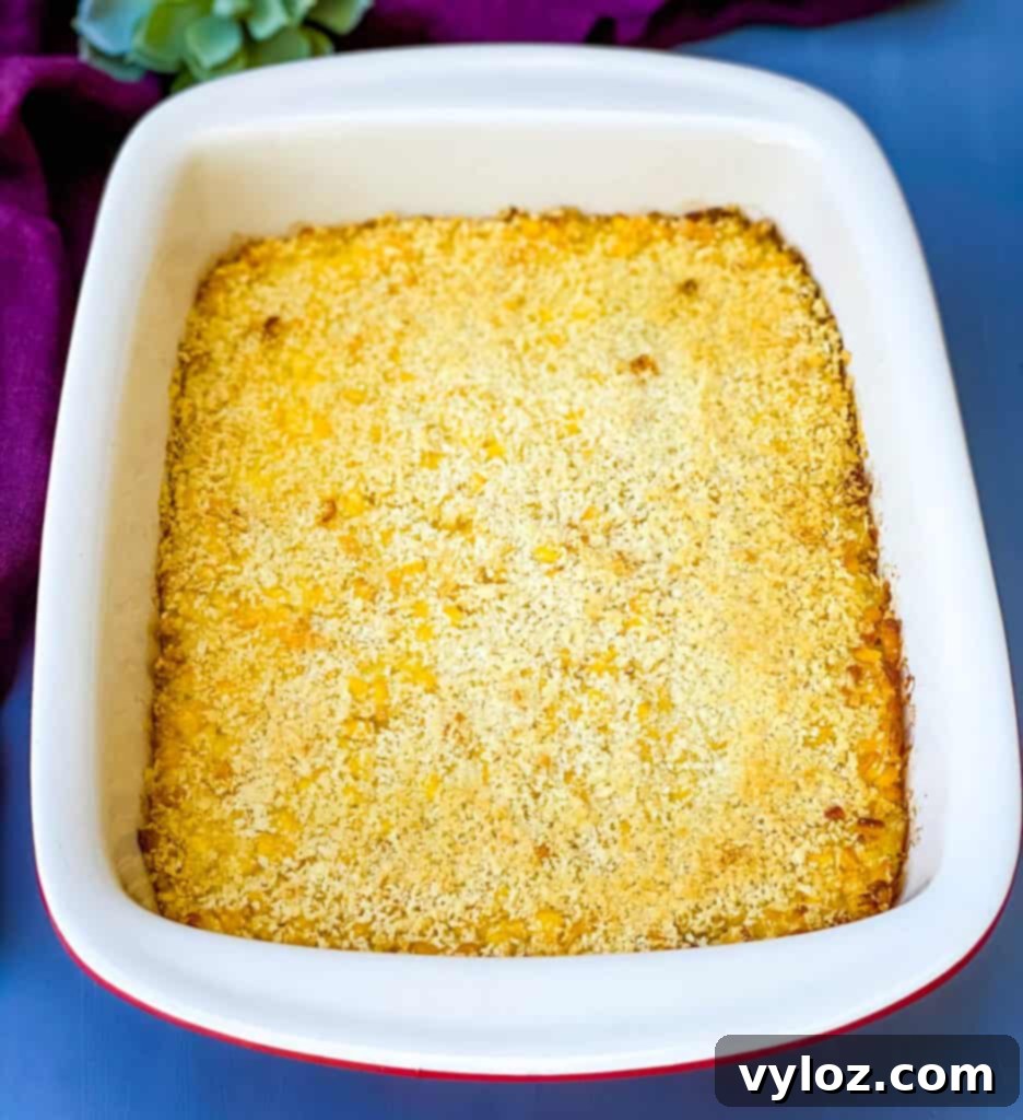 Freshly baked scalloped corn casserole in a vibrant red baking dish, golden brown and bubbling, ready to be served.
