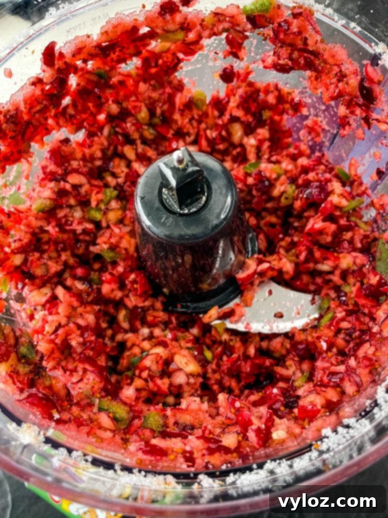 Finely pulsed cranberry jalapeno mixture in a food processor, ready to be layered over cream cheese.