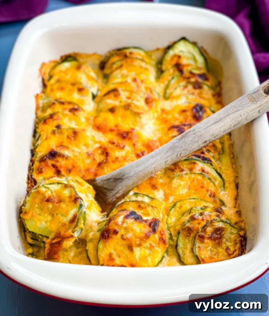 wooden spoon of zucchini au gratin scalloped potatoes in a red baking dish