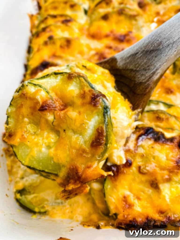 wooden spoon of zucchini au gratin scalloped potatoes in a red baking dish