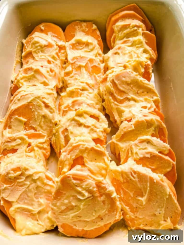 uncooked au gratin sweet potatoes in a red baking dish