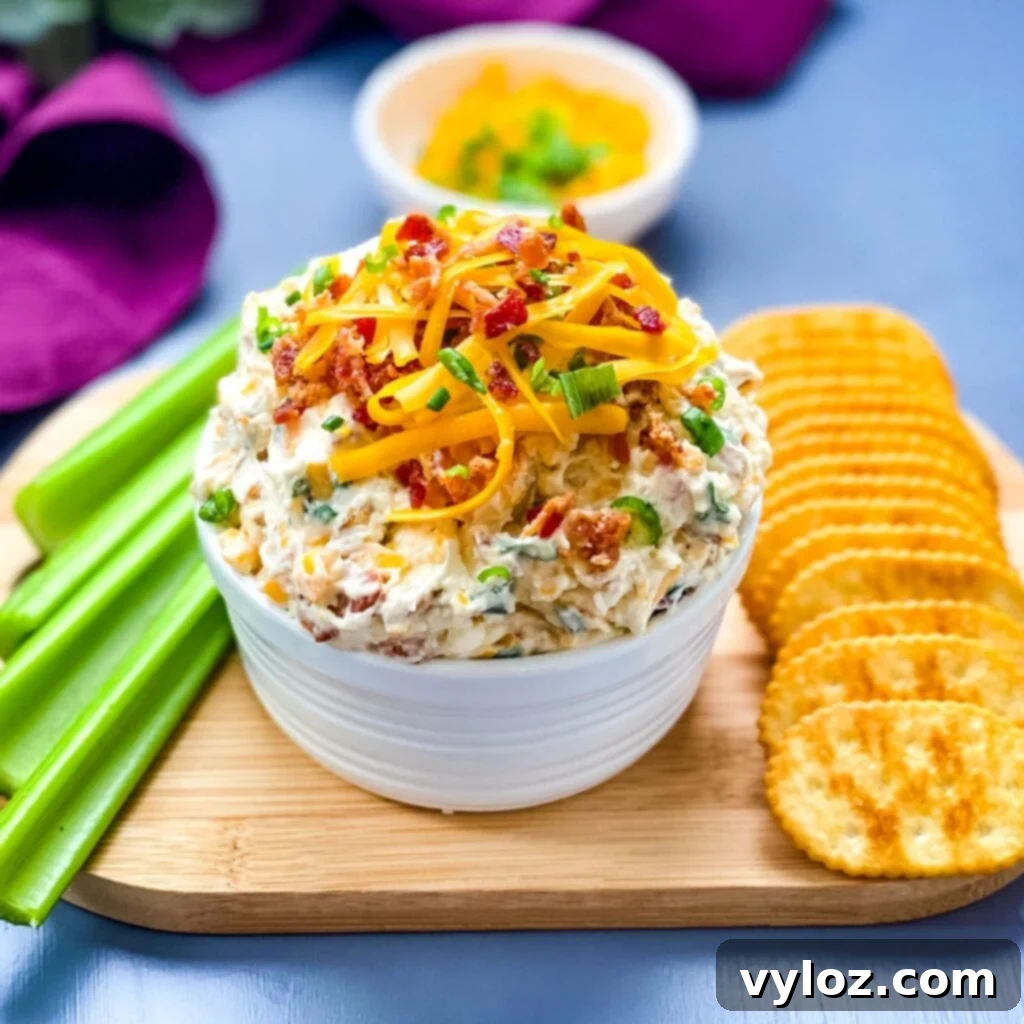 A bowl of Million Dollar Dip garnished with crackers and celery, ready to be served.