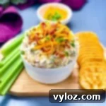 Million Dollar Dip in a white bowl garnished with crackers and celery