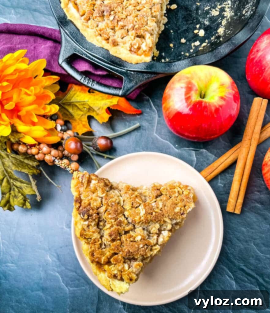 a slice of apple pie on a pink plate with fresh apples