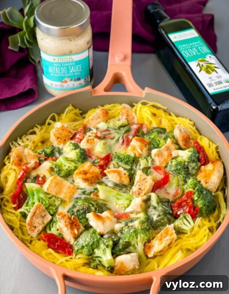 Spaghetti squash chicken alfredo in a pan with broccoli, spinach, and sundried tomatoes