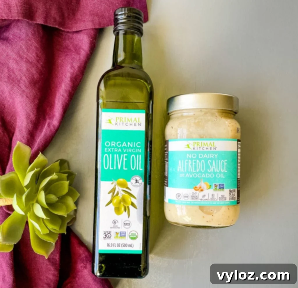 primal kitchen olive oil and alfredo sauce in jars on a flat surface