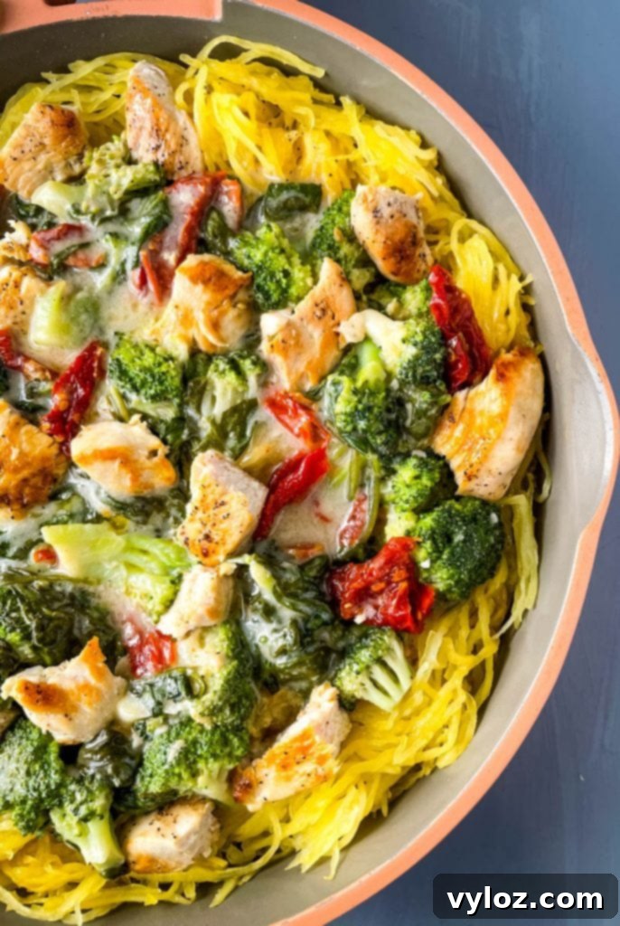 Spaghetti squash chicken alfredo in a pan with broccoli, spinach, and sundried tomatoes