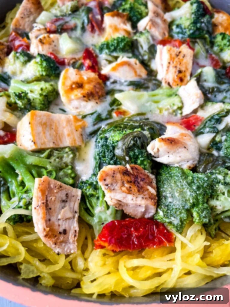 Spaghetti squash chicken alfredo in a pan with broccoli, spinach, and sundried tomatoes